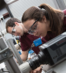 Male and female students with protective eye gears working together in a lab.