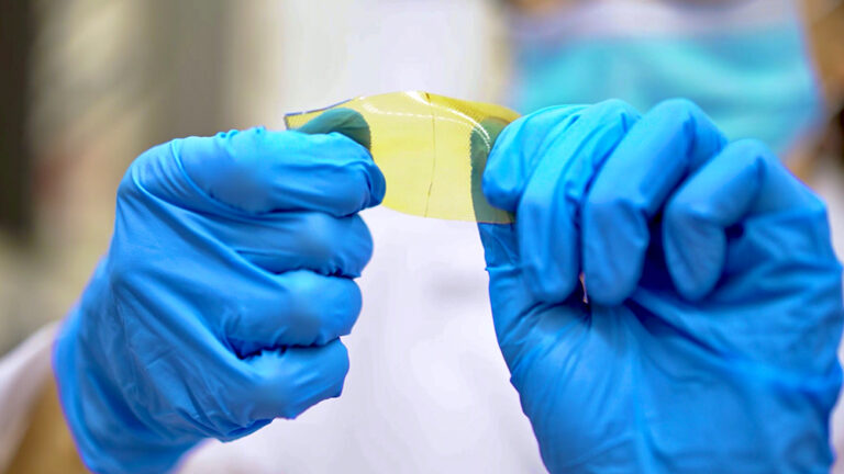 A pair of gloved hands holding a piece of material