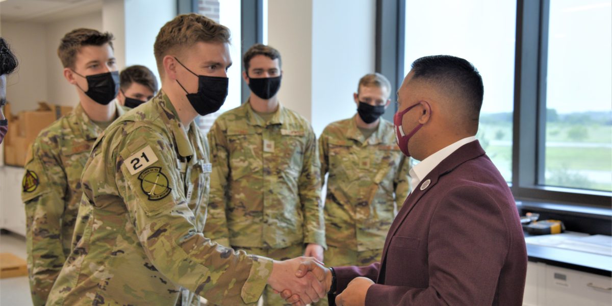 Ross Guieb, BCDC executive director, passes a BCDC challenge coin to Cadet Jon Gabriel, USAFA cadet, during the cadets' visit to Texas A&M University to test their senior engineering capstone design project.