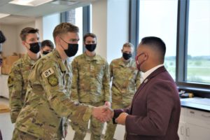 Ross Guieb, BCDC executive director, passes a BCDC challenge coin to Cadet Jon Gabriel, USAFA cadet, during the cadets' visit to Texas A&M University to test their senior engineering capstone design project.