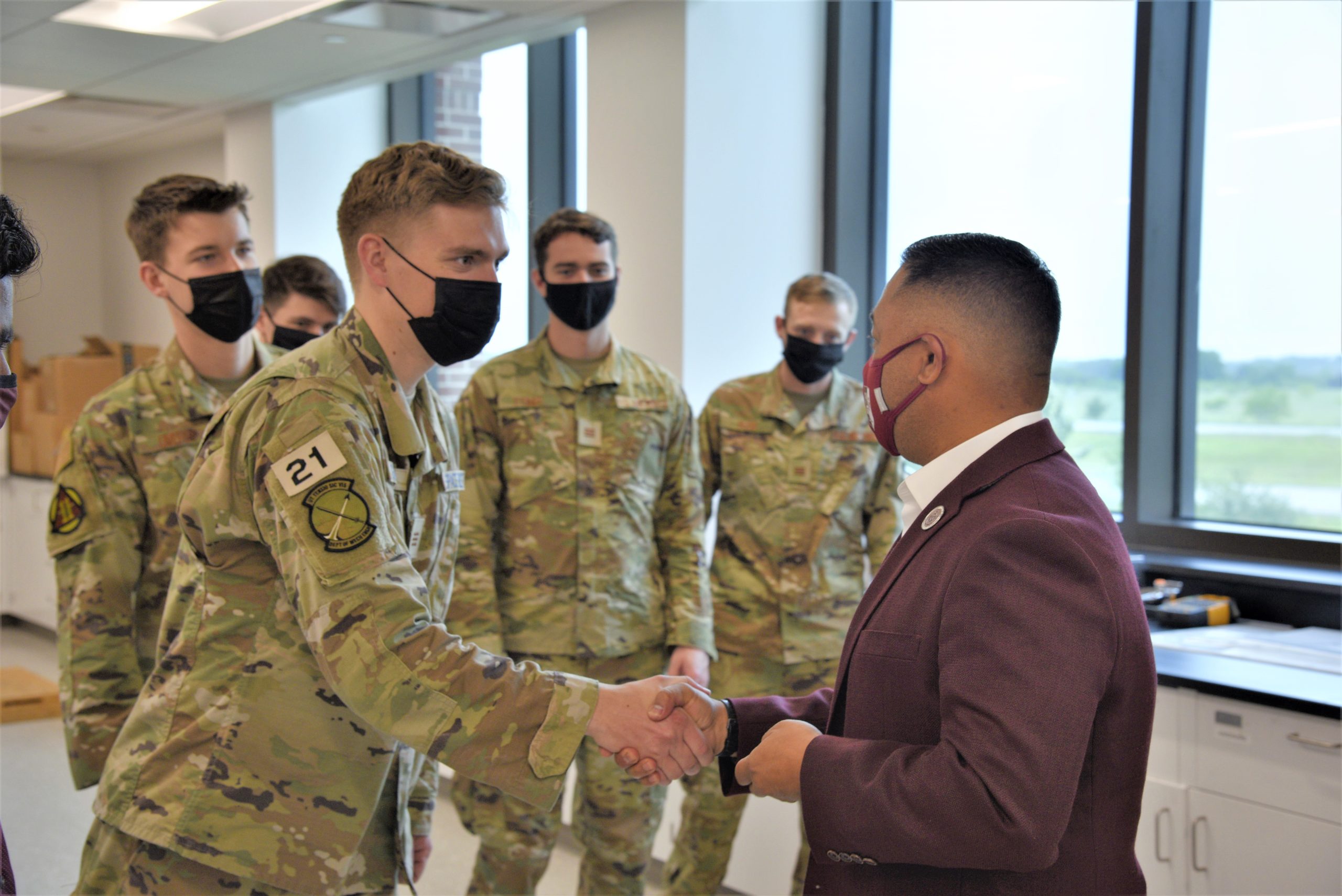 Ross Guieb, BCDC executive director, passes a BCDC challenge coin to Cadet Jon Gabriel, USAFA, during the cadets' visit to Texas A&M University to test their senior engineering capstone design project.