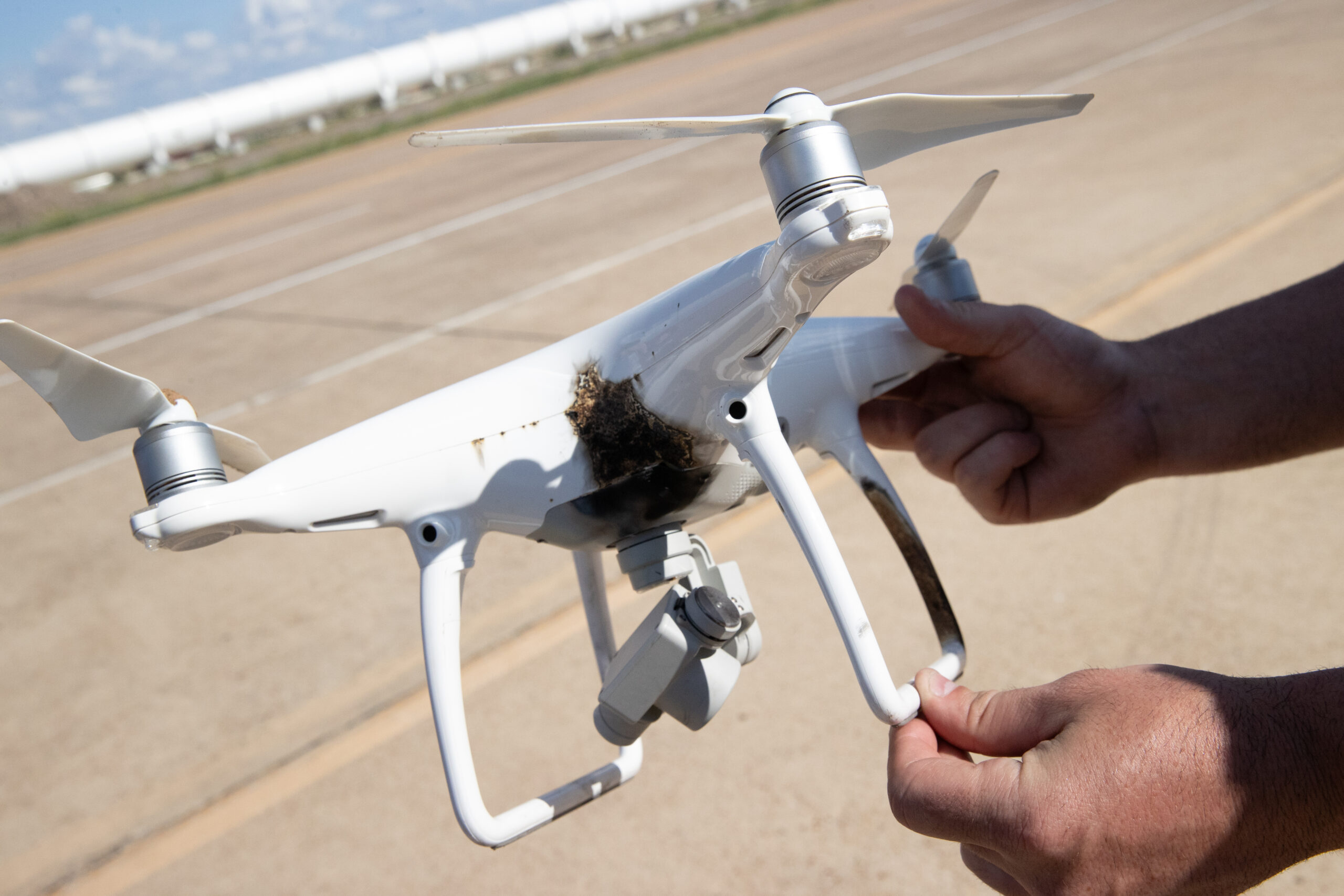 Damaged aerial drone held by two hands.