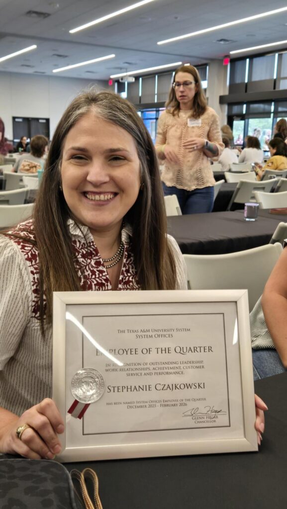 Woman holding the Texas A&M University System Offices Employee of the Quarter award.